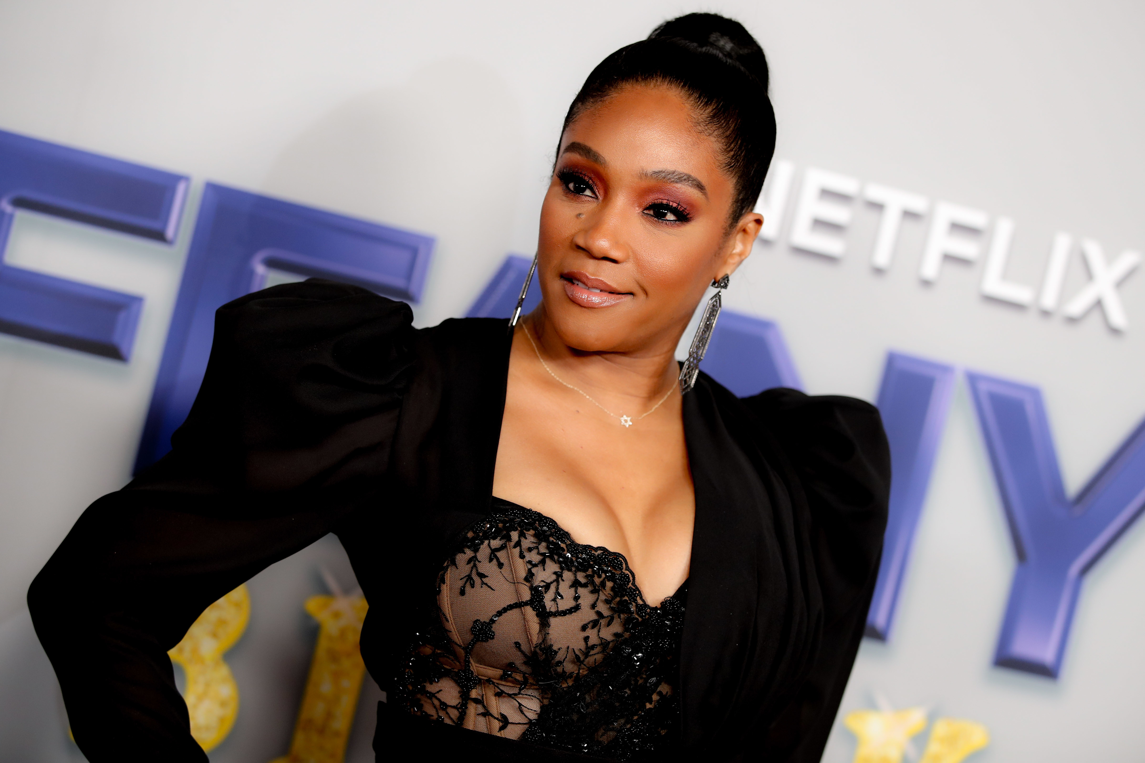 A red carpet image of Tiffany Haddish dressed in black and posing for the camera