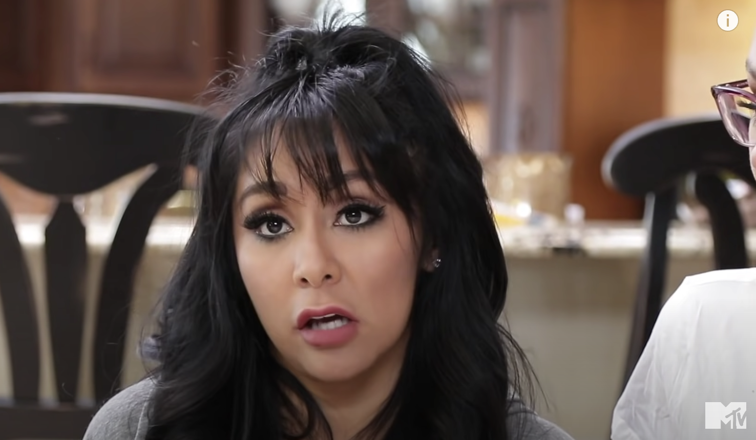 A screenshot of Snooki sitting on a couch and looking into the camera while talking