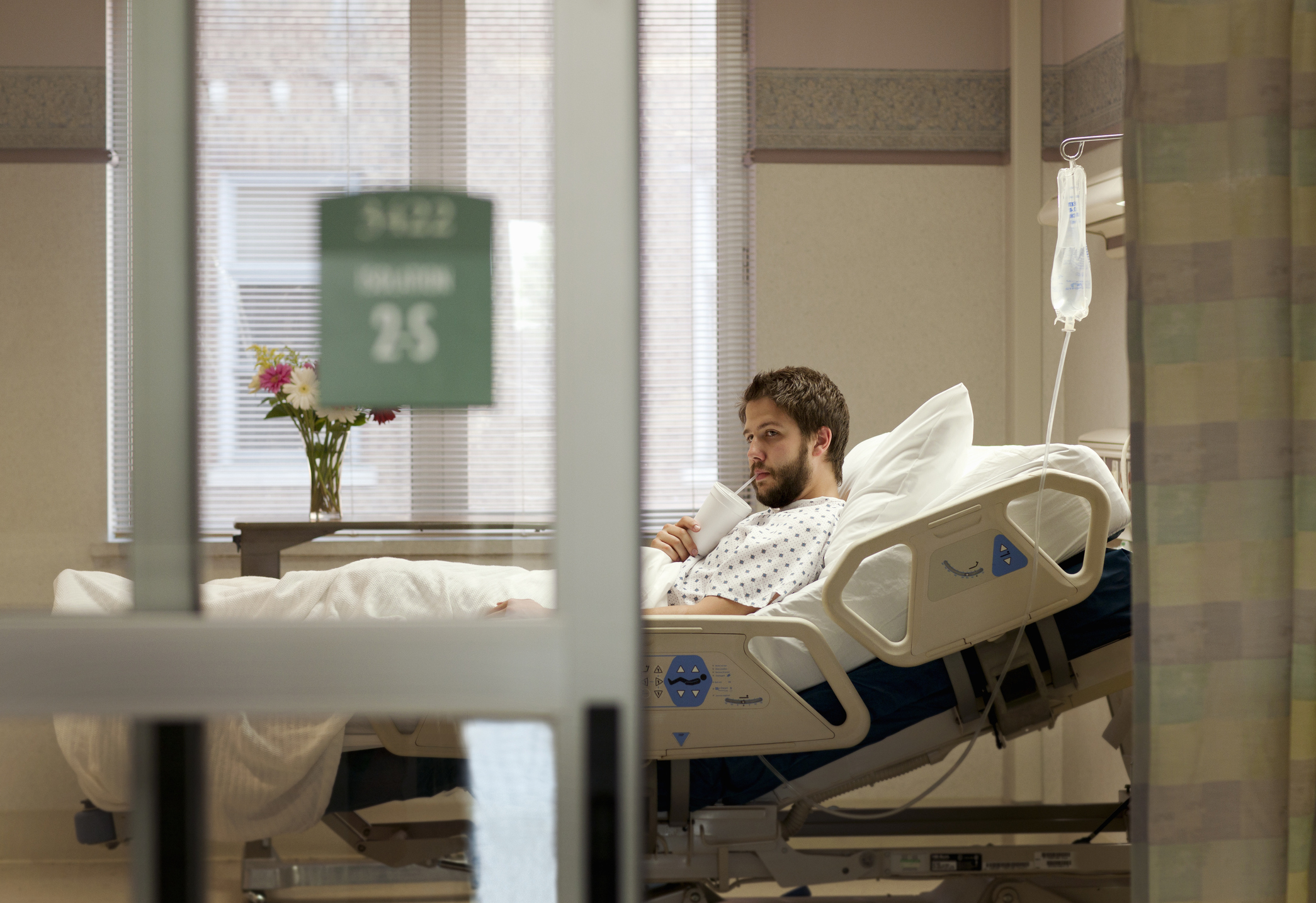 Man drinking beverage in hospital bed