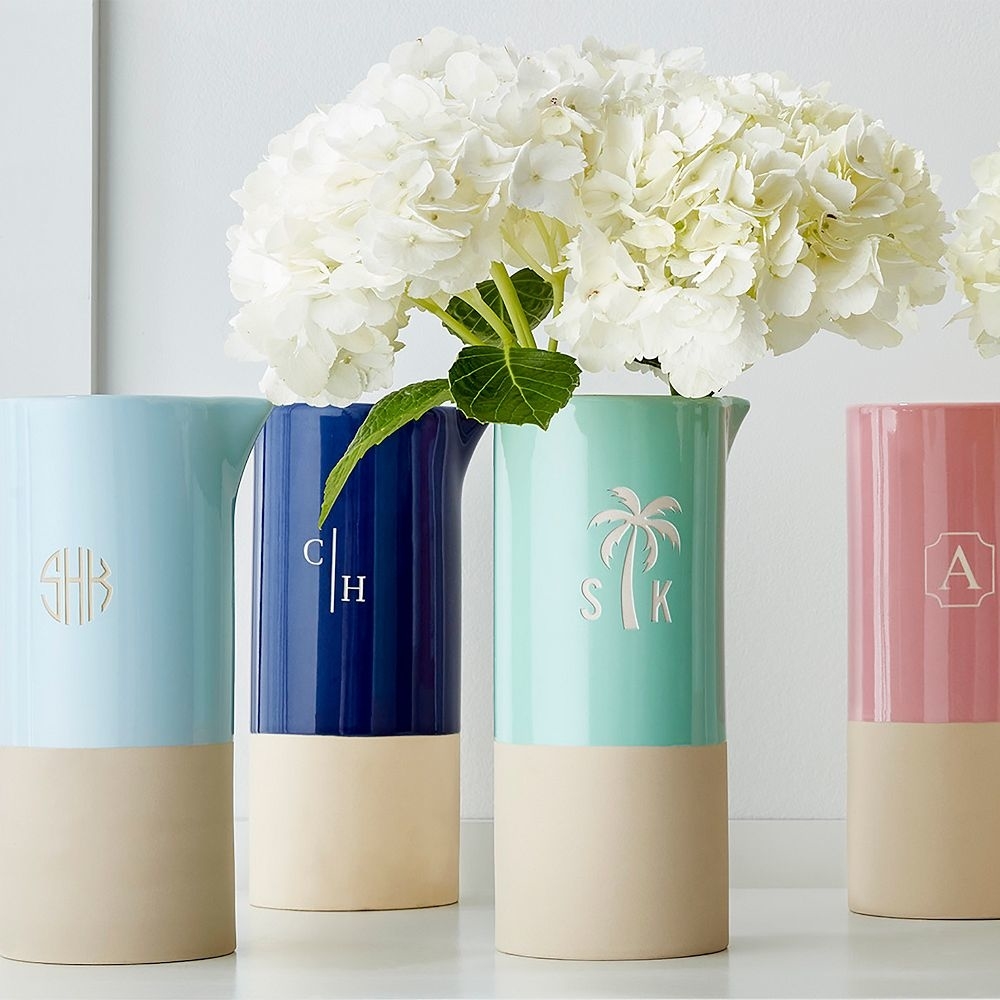 A collection of colorful monogrammed pitcher vases