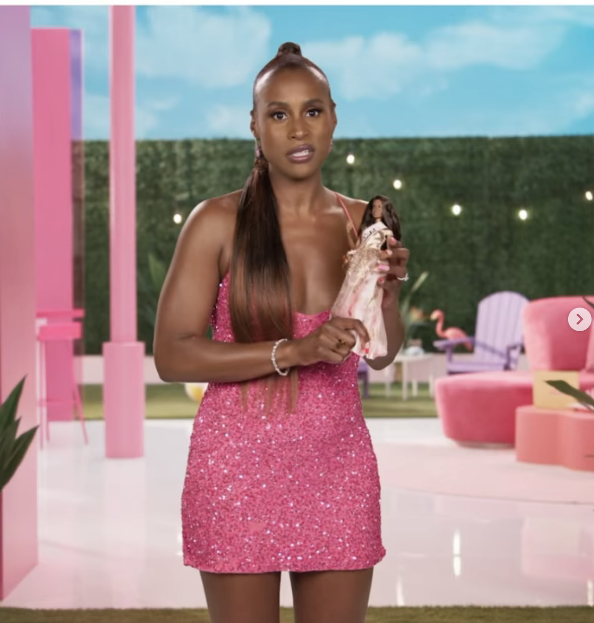 Issa holding a Barbie while wearing the sparkly minidress