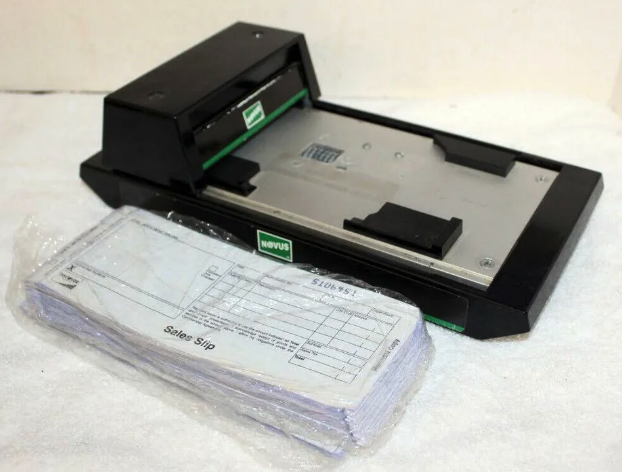 manual credit card machine with sales slips next to it