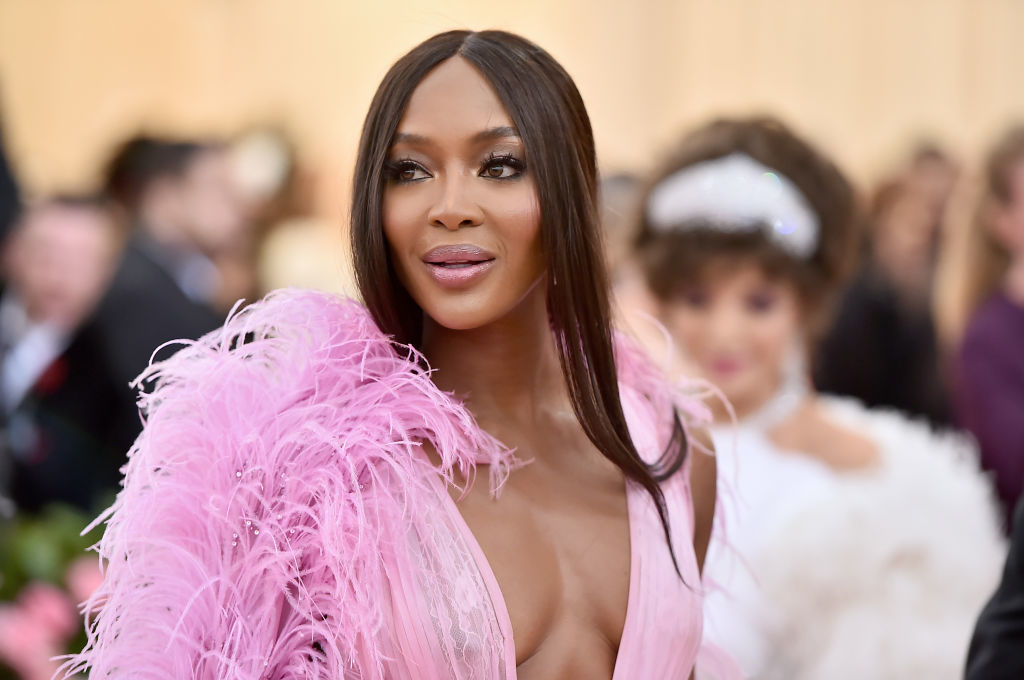 Naomi on the red carpet wearing a feathered gown with a deep v-cut