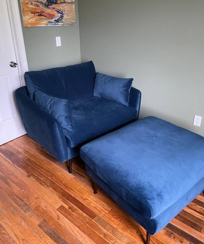 blue velvet loveseat with two side pillows and an ottoman