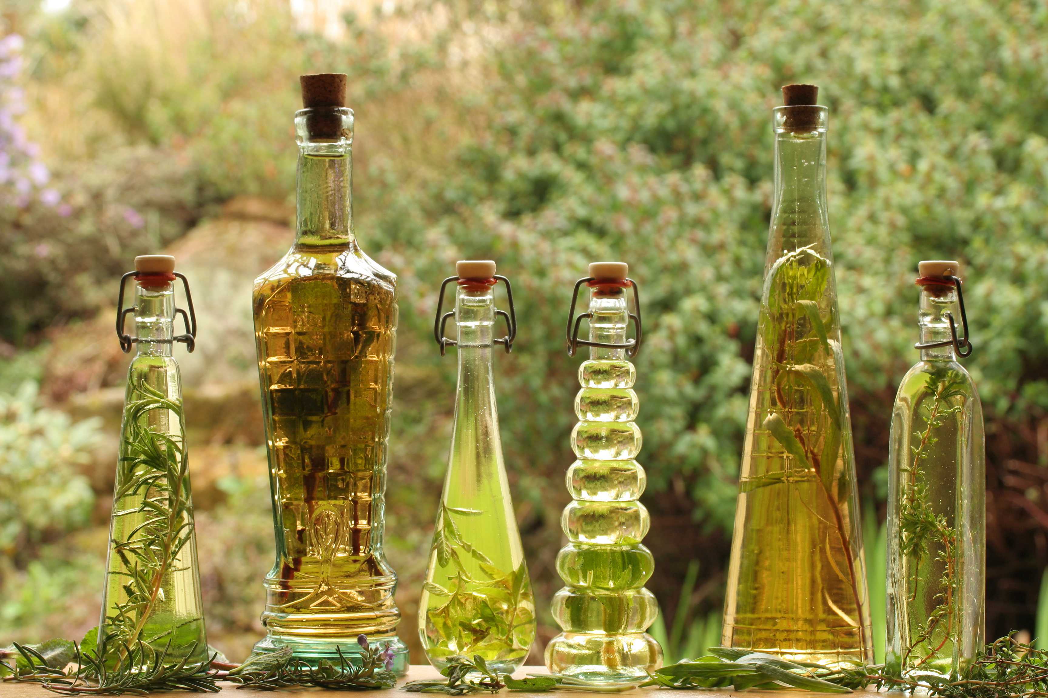 Close-up of decorative oil and vinegar bottles against a verdant outdoor background