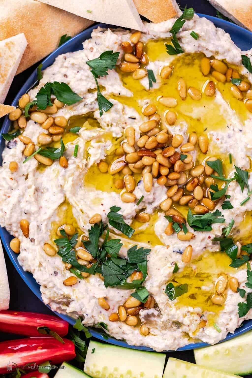baba ganoush dip topped with olive oil, herbs, and pine nuts