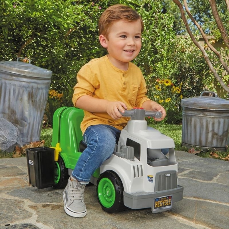 Child rides on a toy trash truck