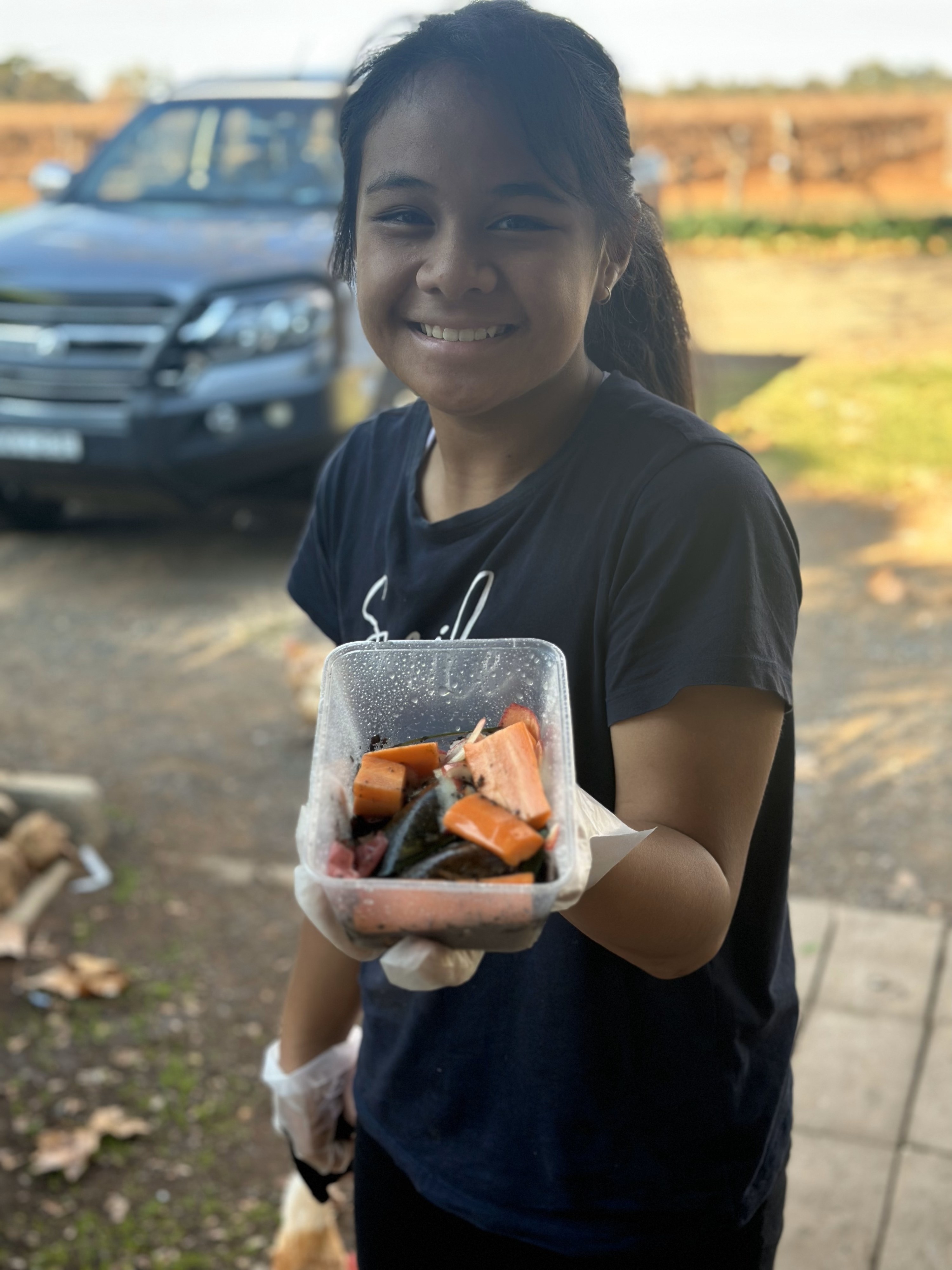 A young girl holding a cart of food scraps