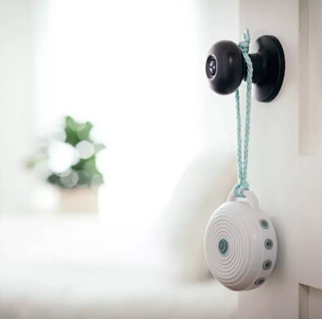 A small and portable sound machine hanging from a doorknob