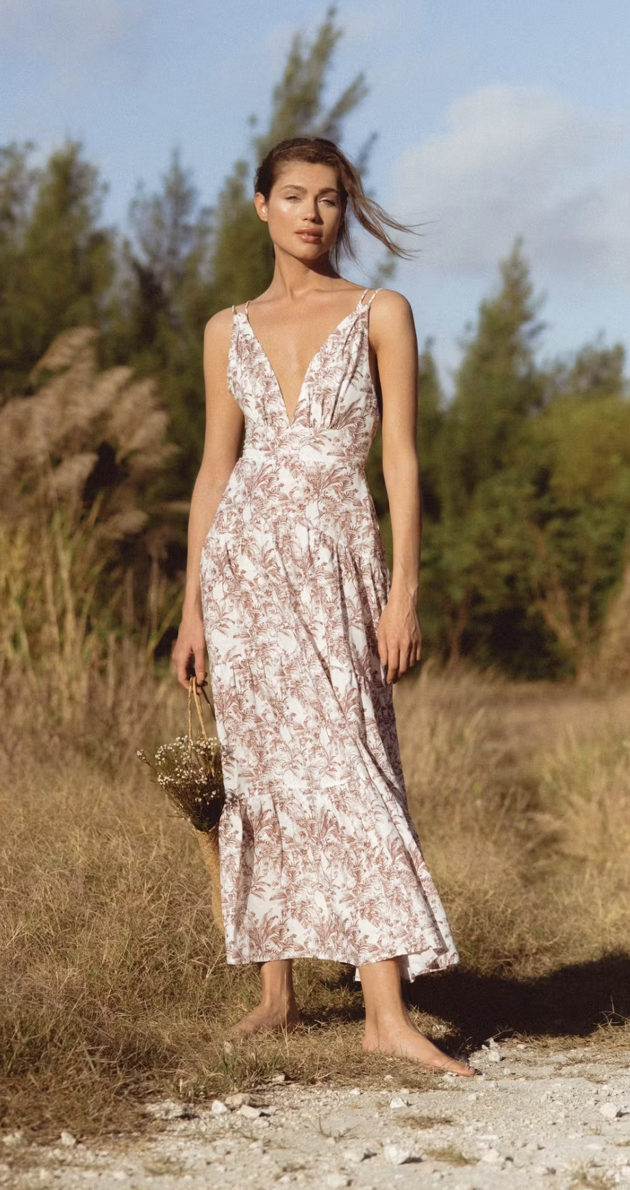 a model wearing the dress in white with a brown floral pattern