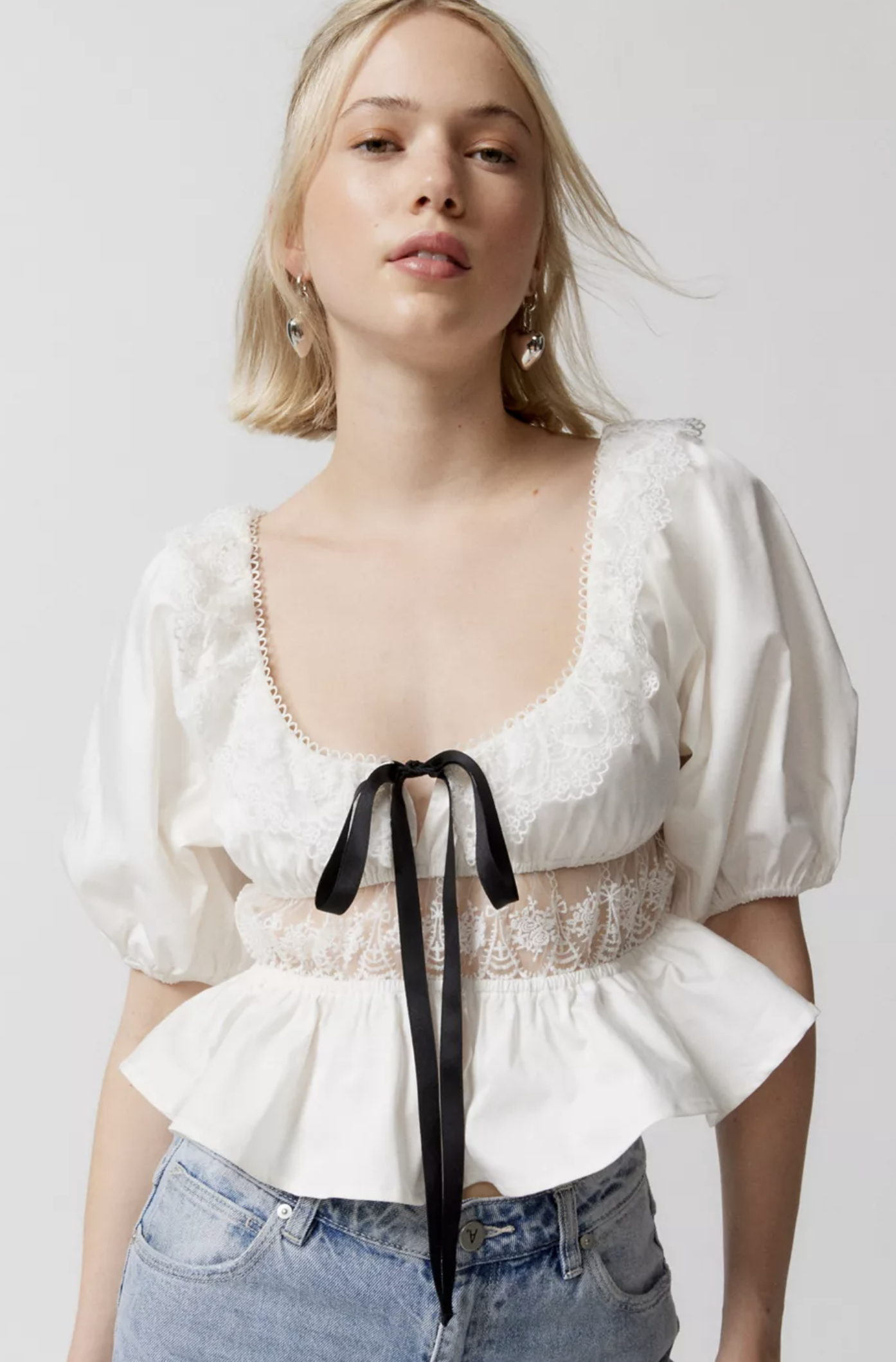 model wearing the shirt in white with a black bow at its center
