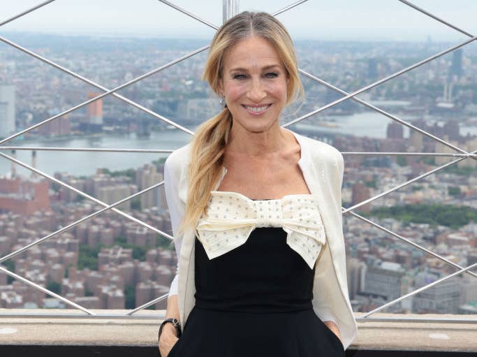 Close-up of SJP smiling with a city scene behind her