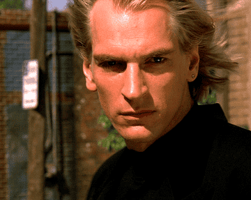 Julian Sands stares intensely in a windy breeze