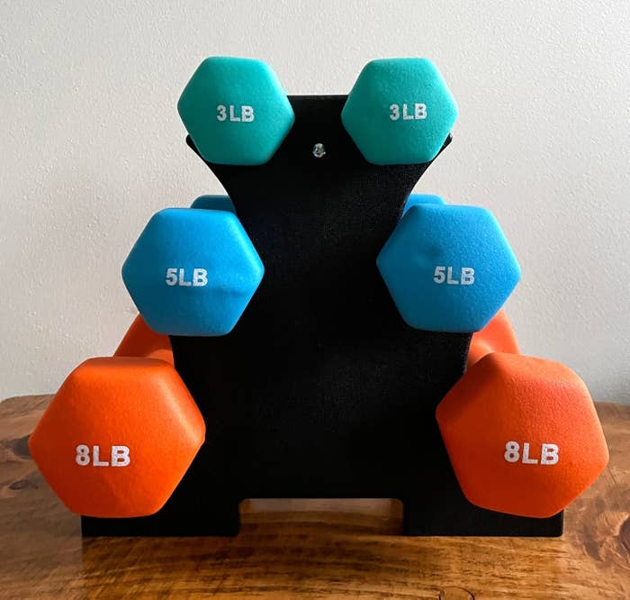 reviewer&#x27;s set of 8-, 5-, and 3-pound weights on a black plastic stand