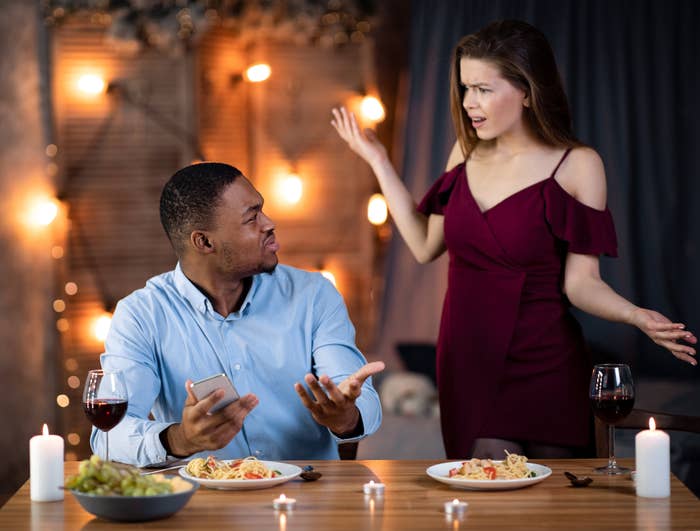 A man sitting at a dining table arguing with a woman standing next to him