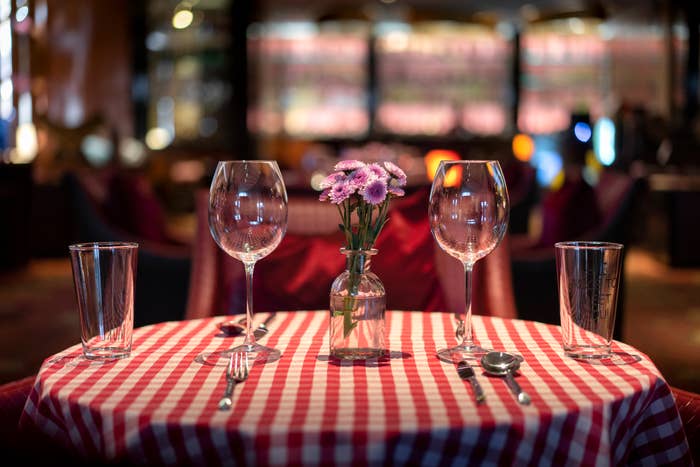 Close-up of two wineglasses and two other glasses on a small, round table with a checkered tablecloth