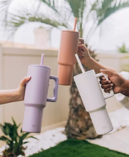 Three hands holding the tumblers in three different colors