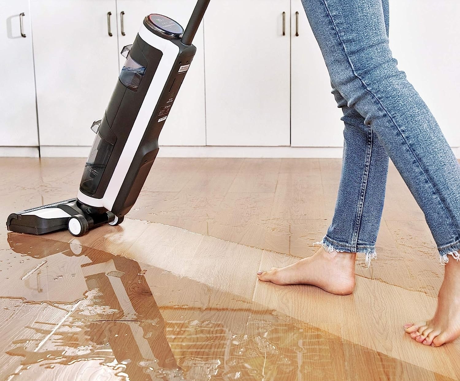 A model using the floor cleaner to mop up water on a hardwood floor