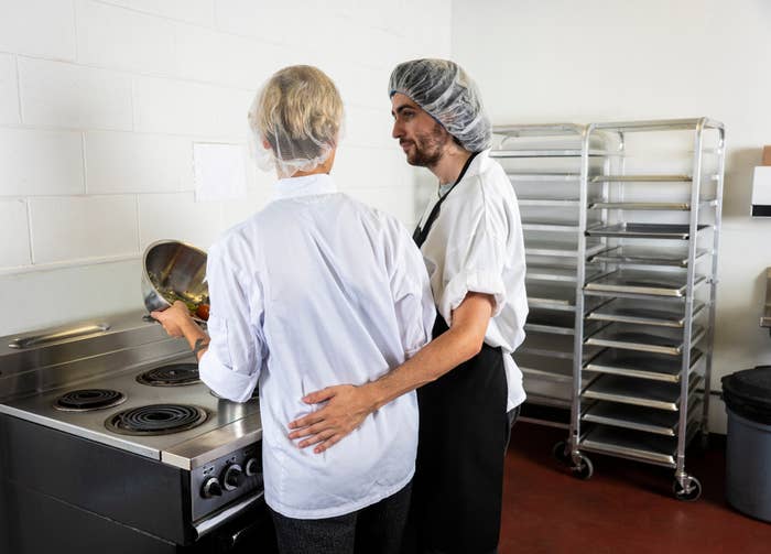 person in the kitchen with their arm around someone&#x27;s lower back