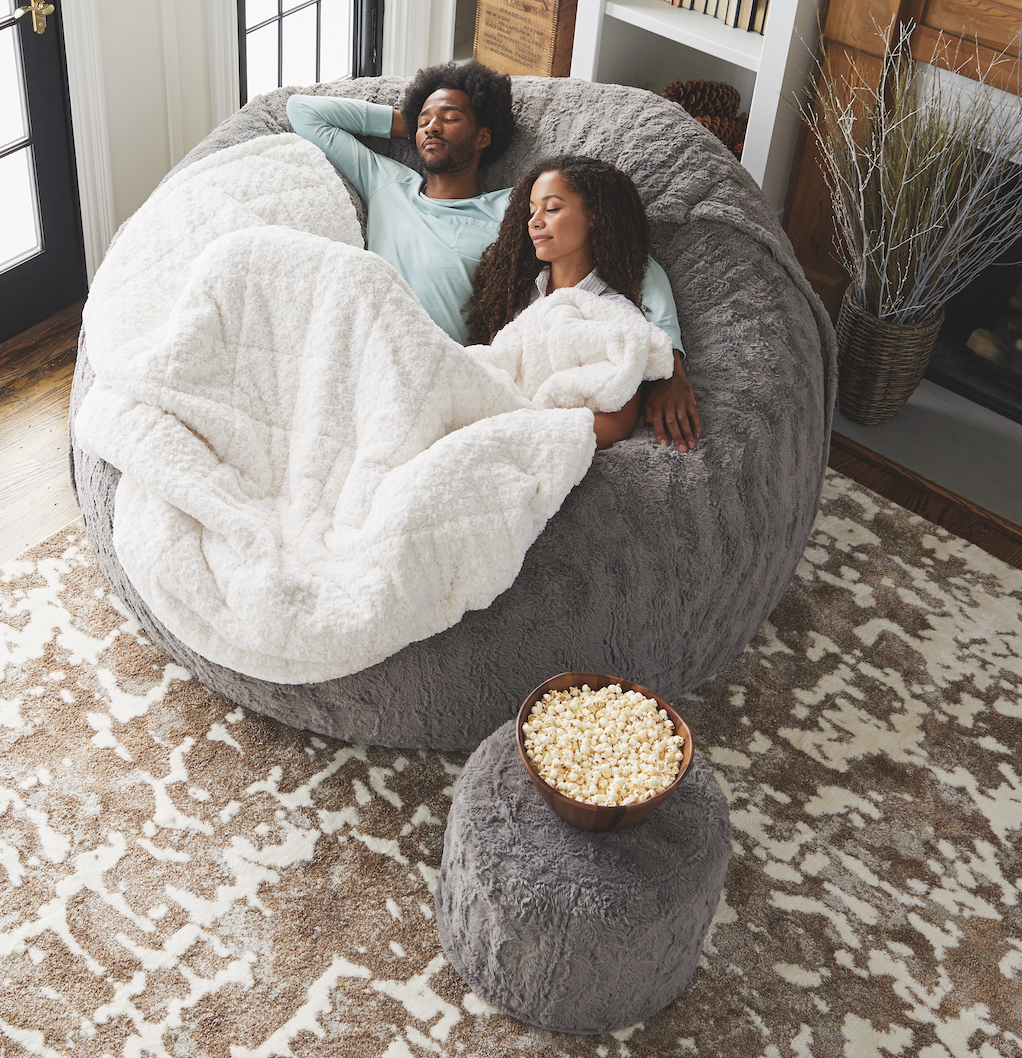 Two people lounge on a big pillow chair