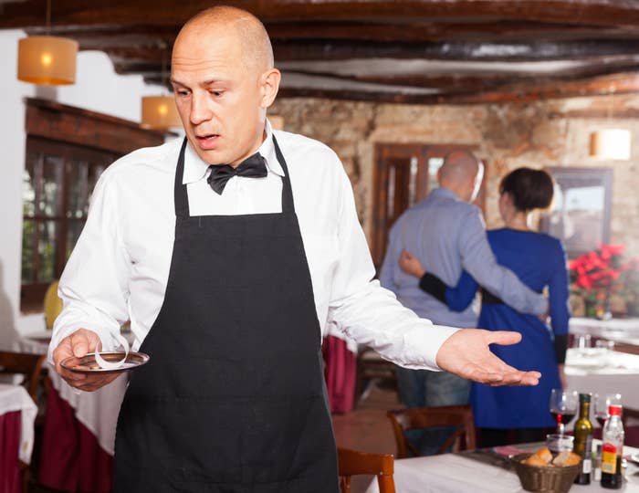 server with his arms up while holding a small dish with the receipt