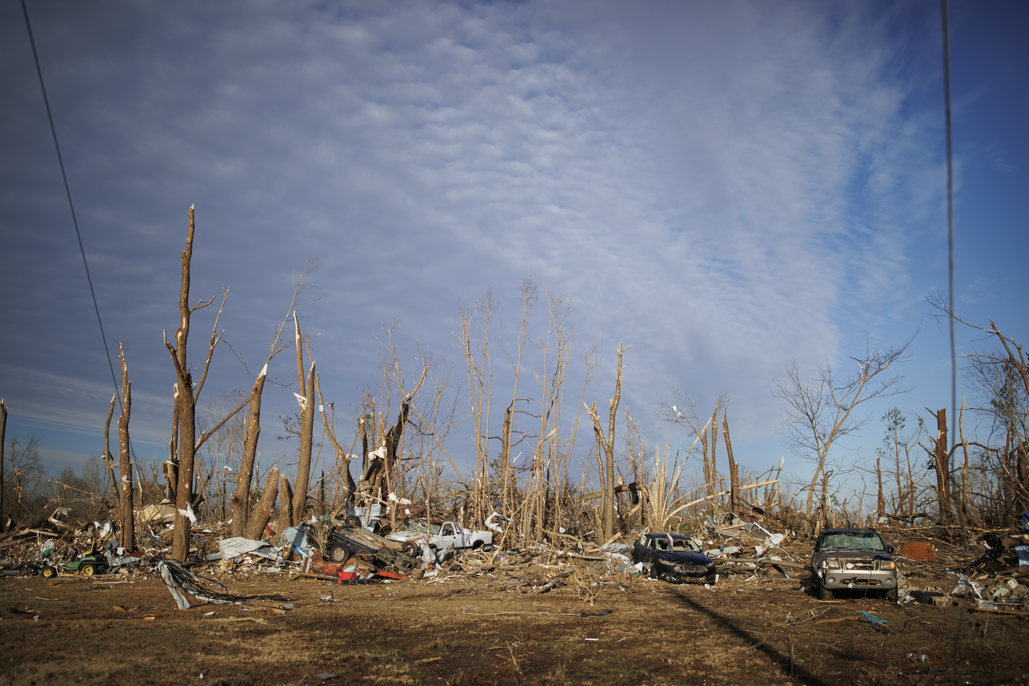 leveled neighborhood from tornado, with cars and trees scattered about