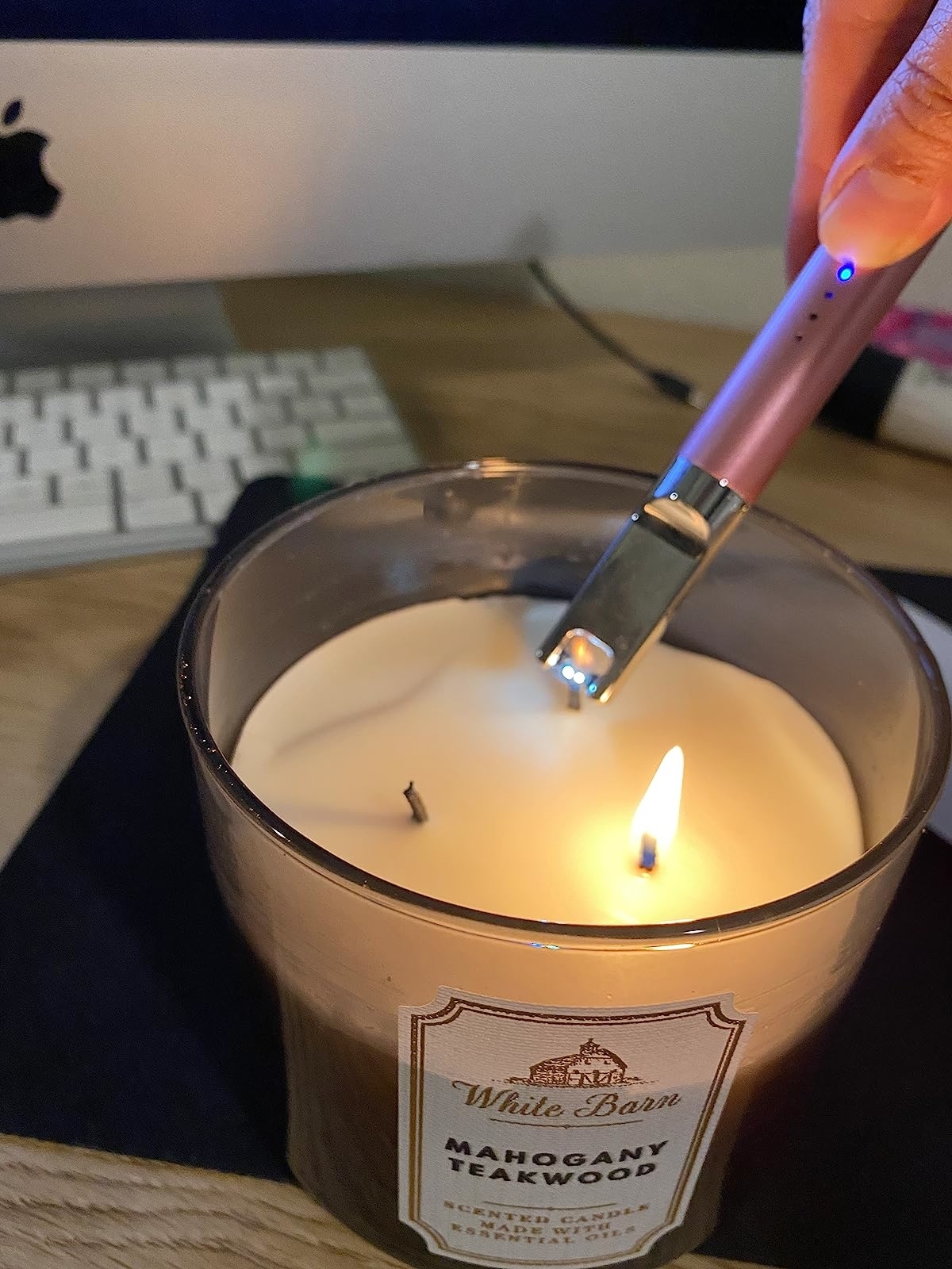 a reviewer photo of the rose gold lighter being used to light a white candle