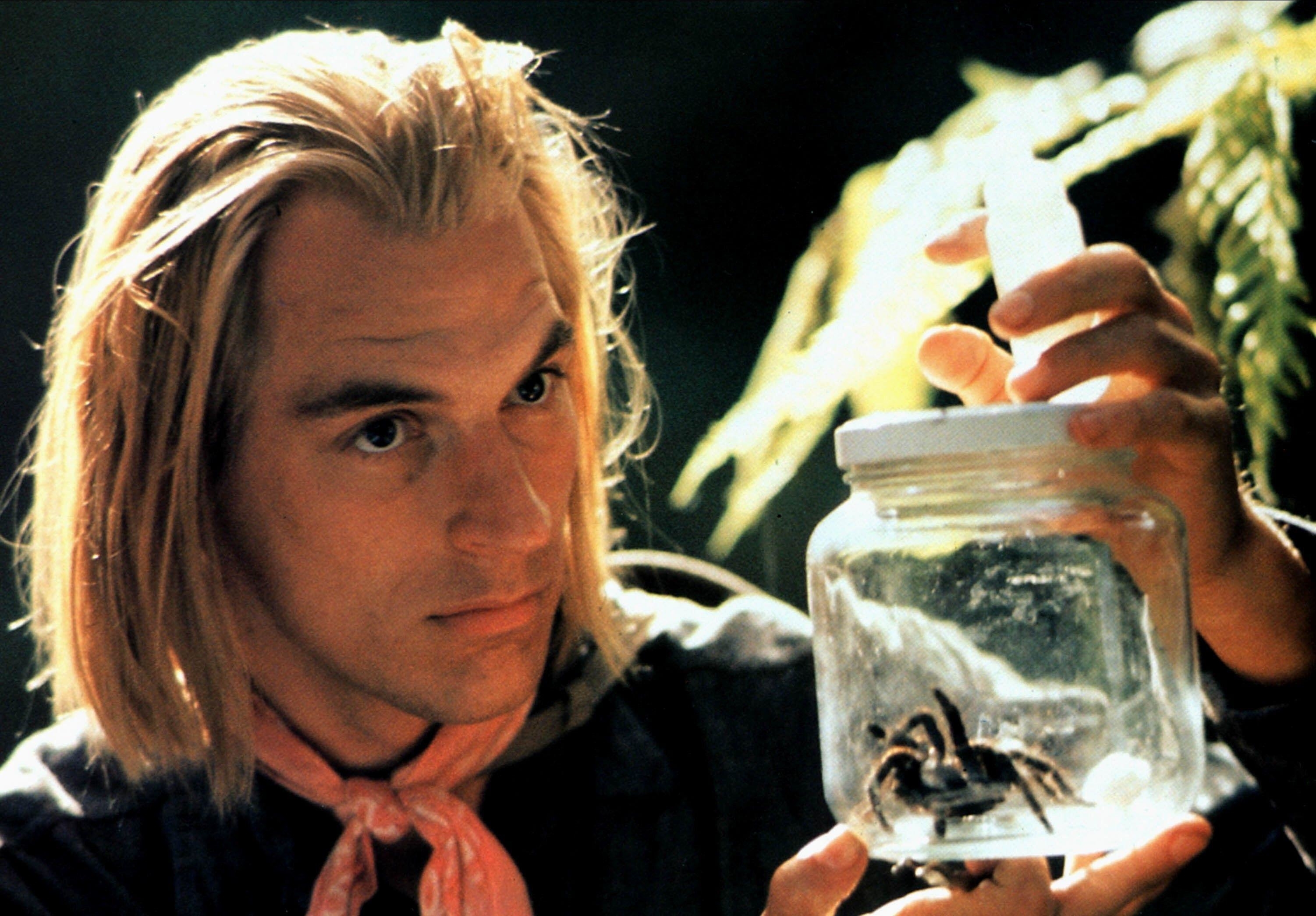 Julian Sands showcases a spider in a jar