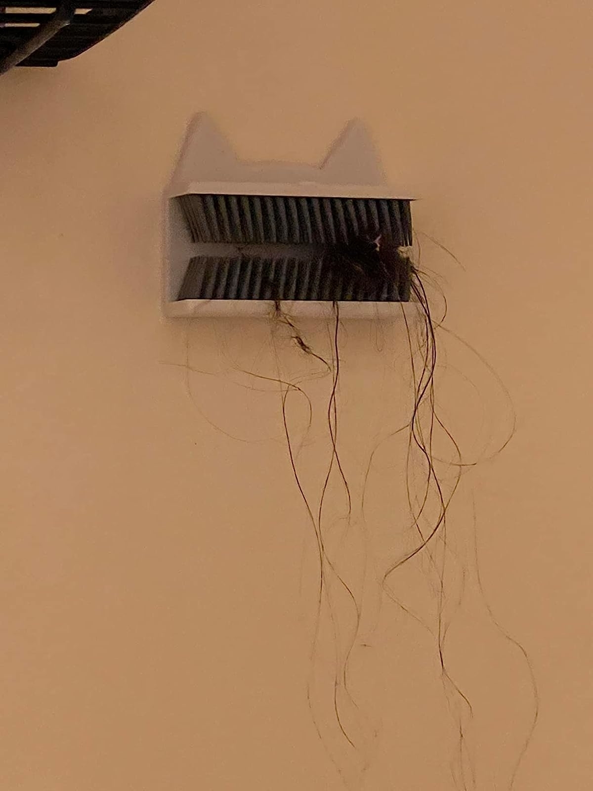 a reviewer photo of the cat-shaped white hair catcher filled with hair after a shower