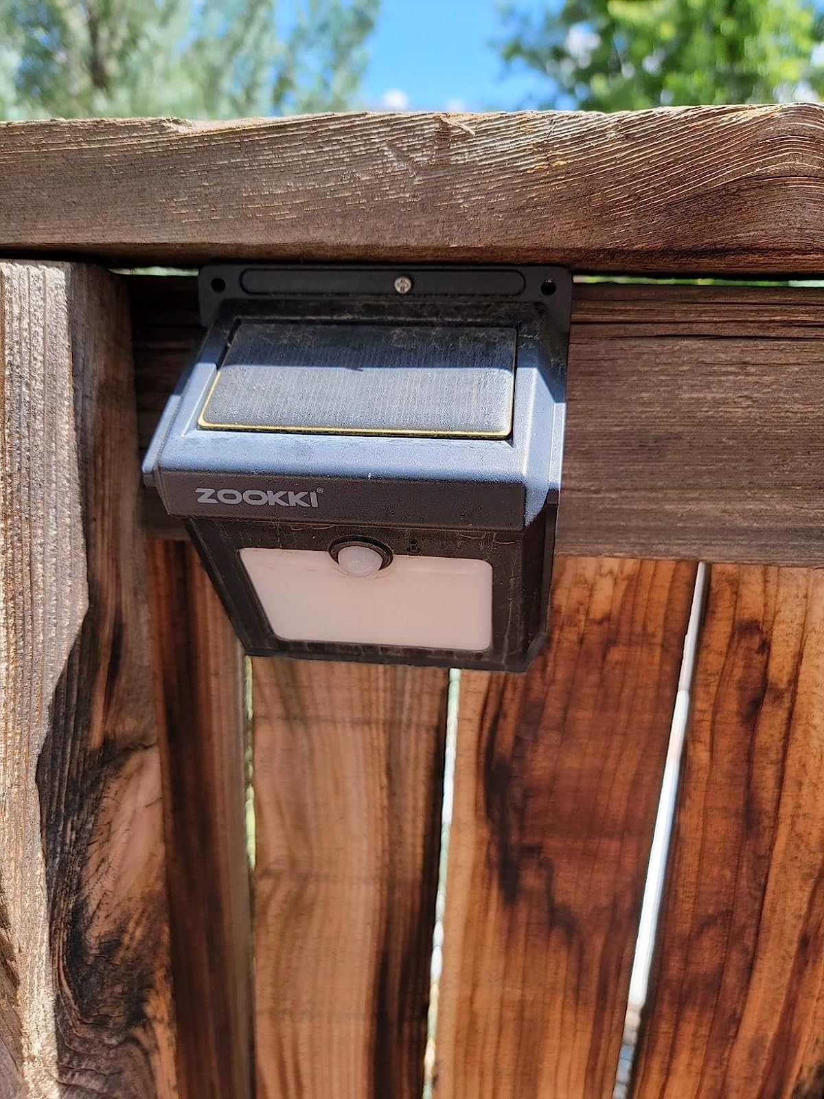 a reviewer photo of the black solar light attached to a wooden fence
