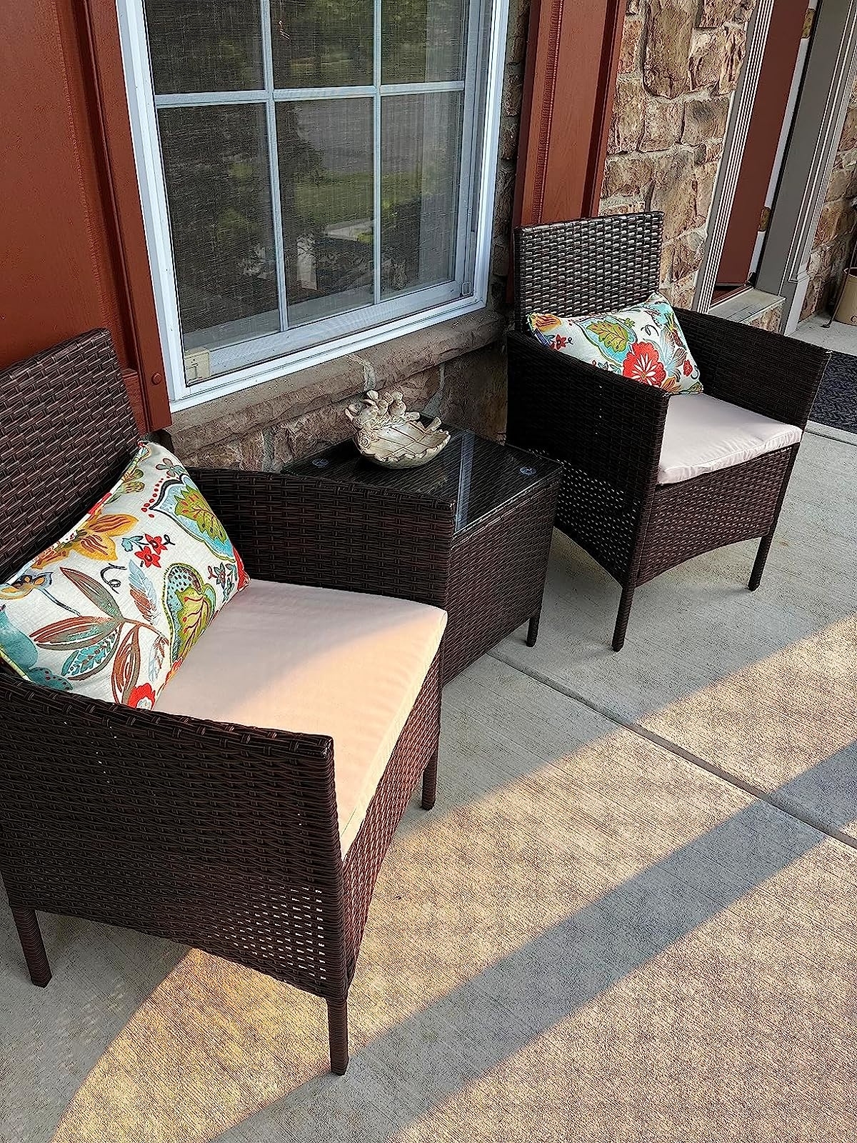 a reviewer photo of the brown wicker table and chairs on a decorated patio space