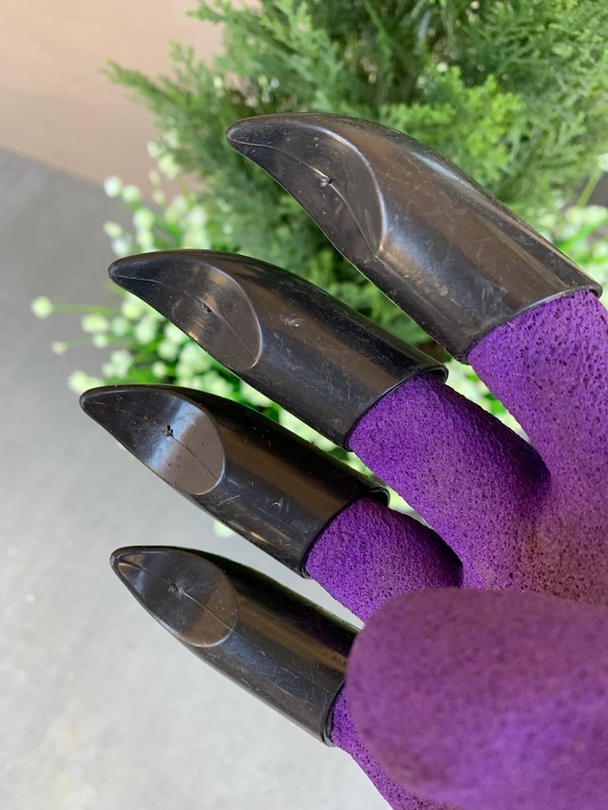 a reviewer photo of a hand wearing the purple gloves with black plastic claws