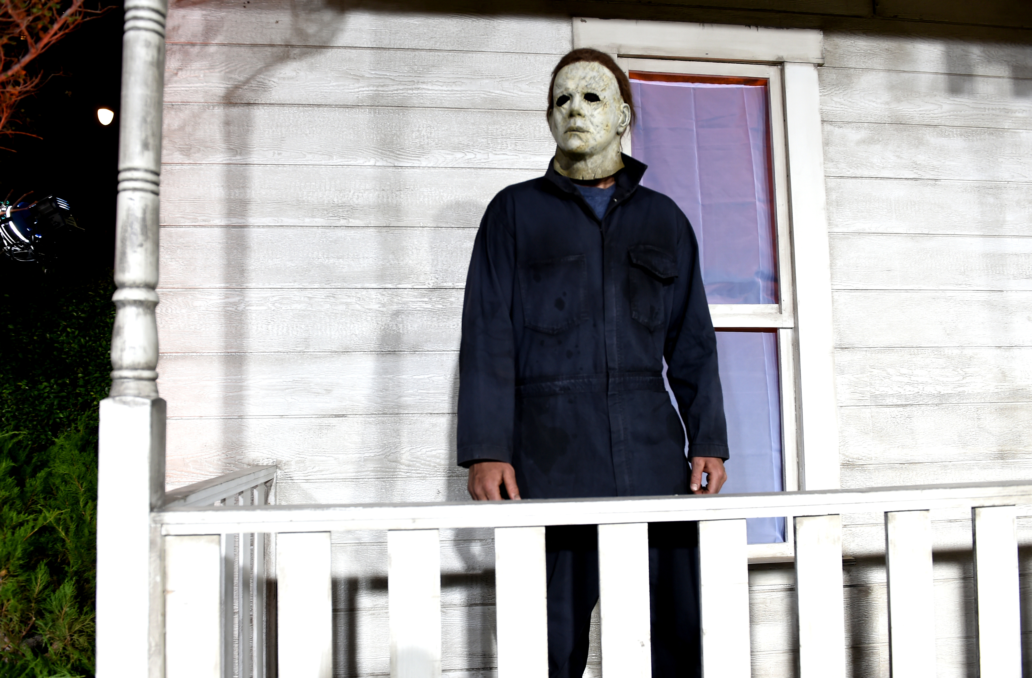 An actor dressed as Michael Myers outside a house
