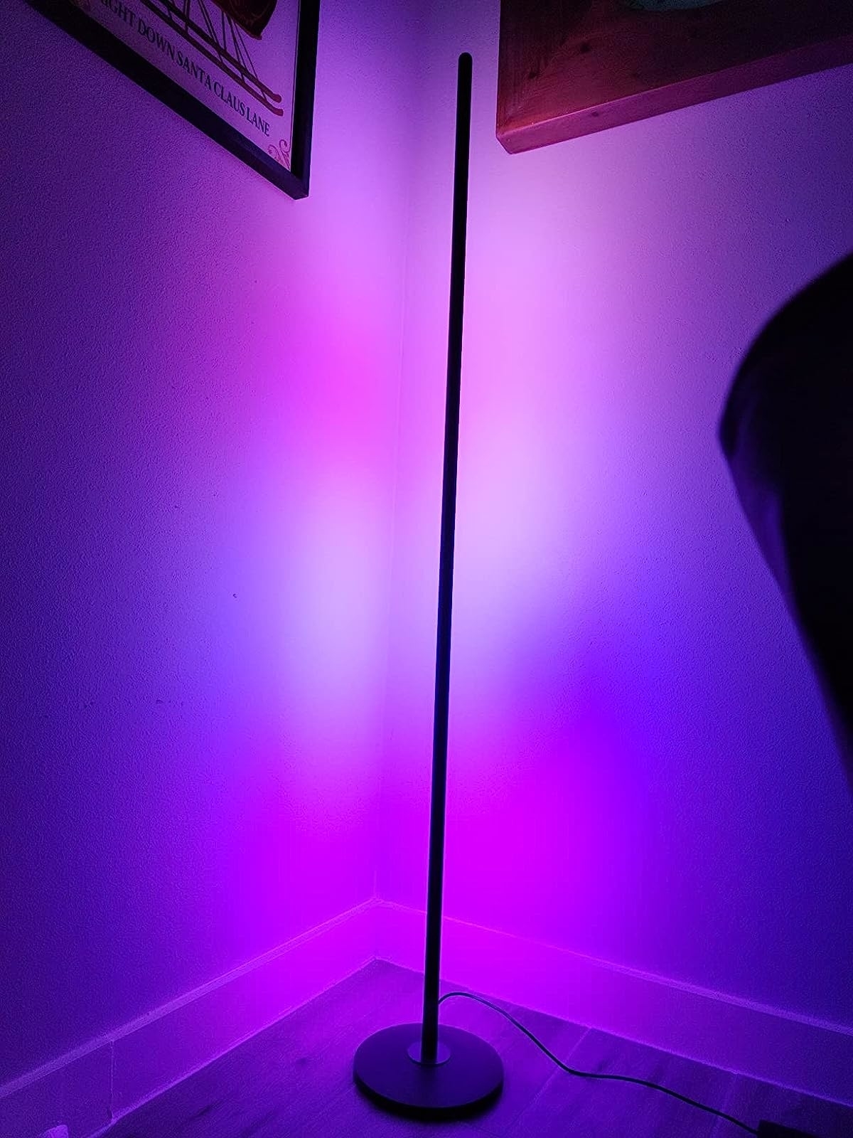 the black rod shaped lamp in a corner showing several shades of purple light