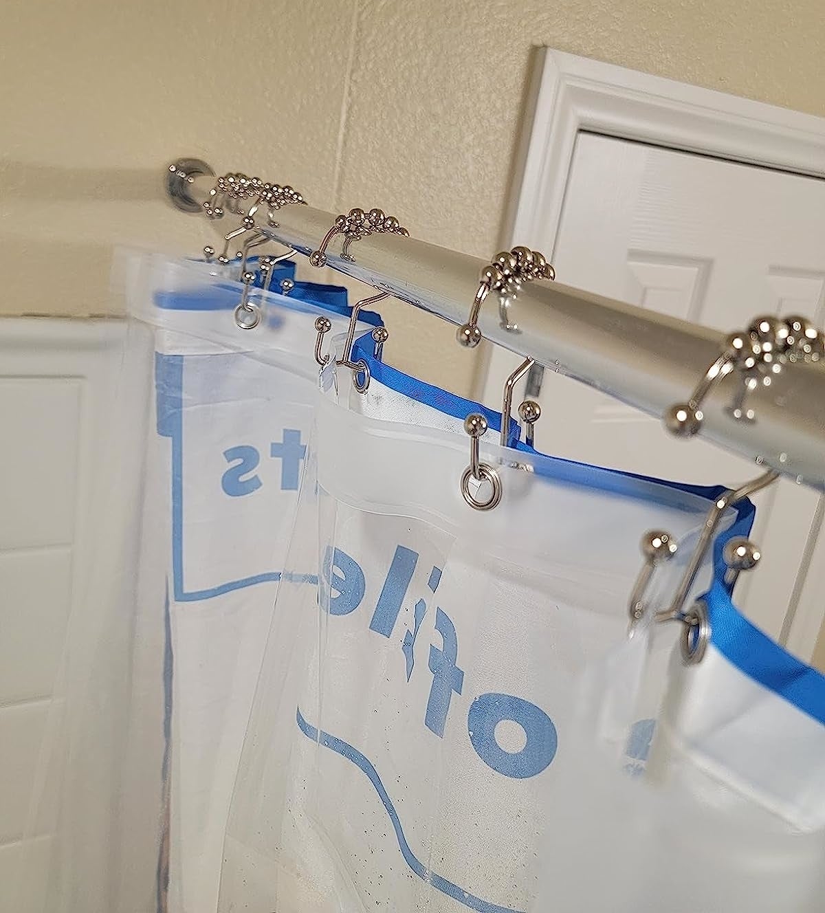 a reviewer photo of the silver double hooks holding up a shower curtain and liner
