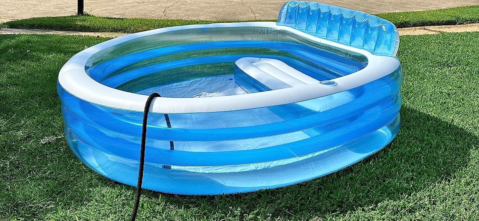 a reviewer photo of the blue and white pool in a backyard with a black hose hanging over the edge