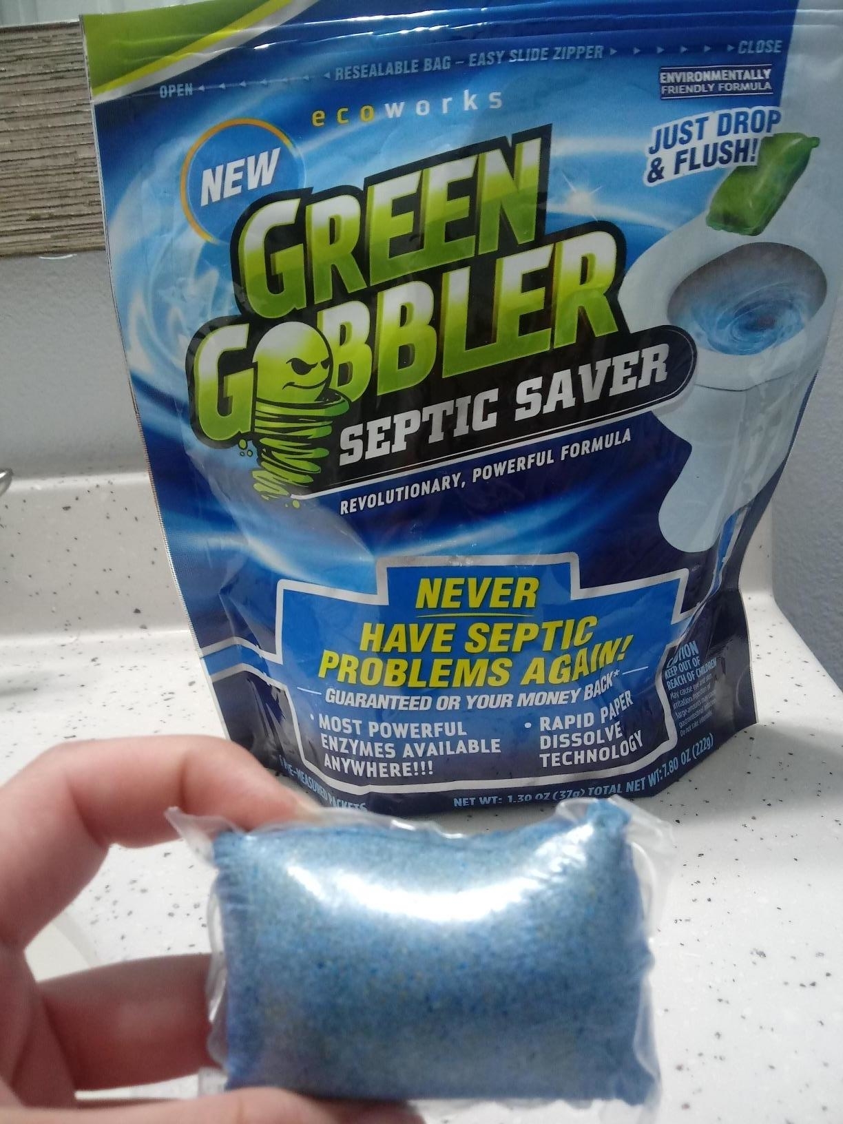 a reviewer photo of a hand holding the blue packet in front of the bag of packaging