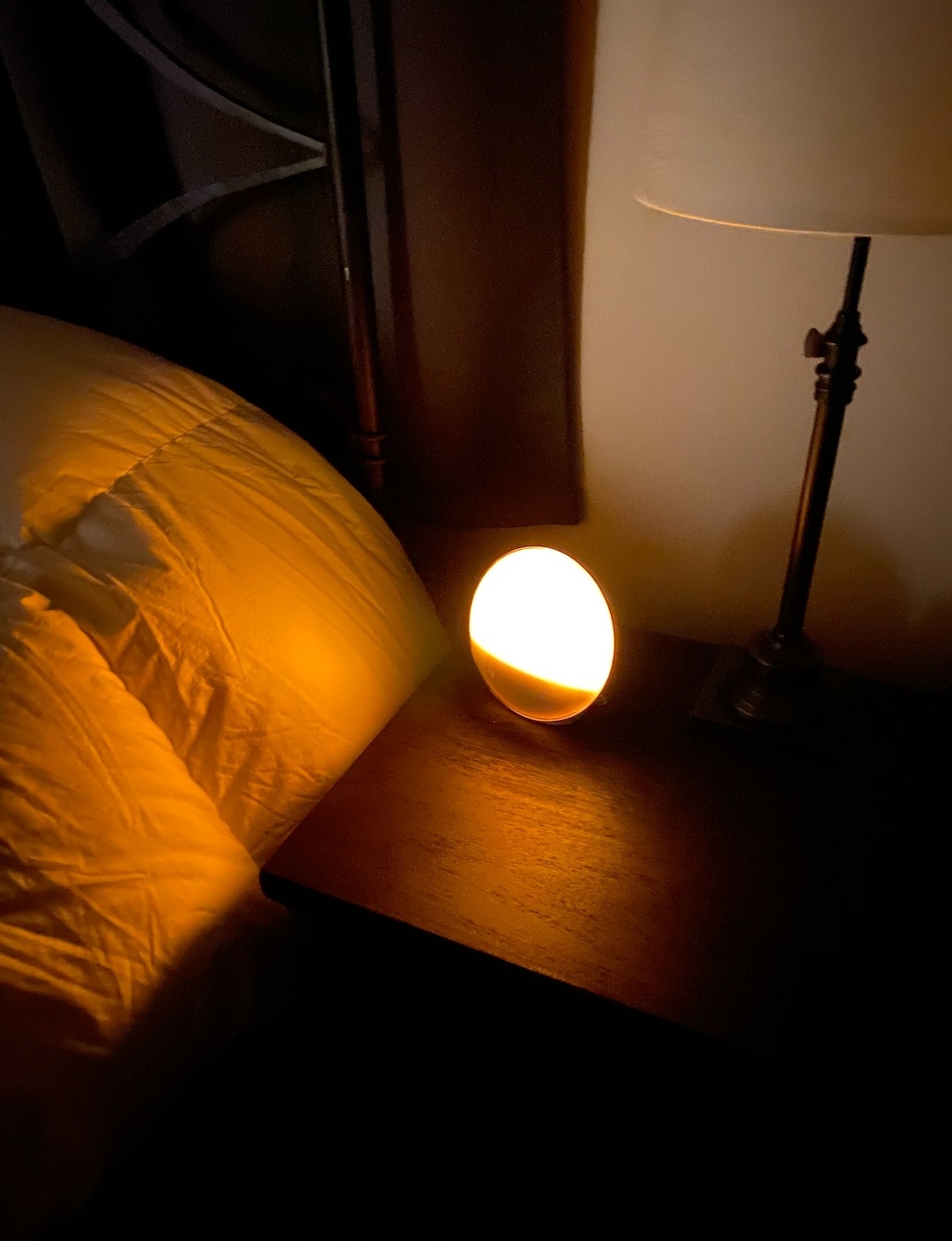 a reviewer photo of the warmly lit alarm clock on a bedside table