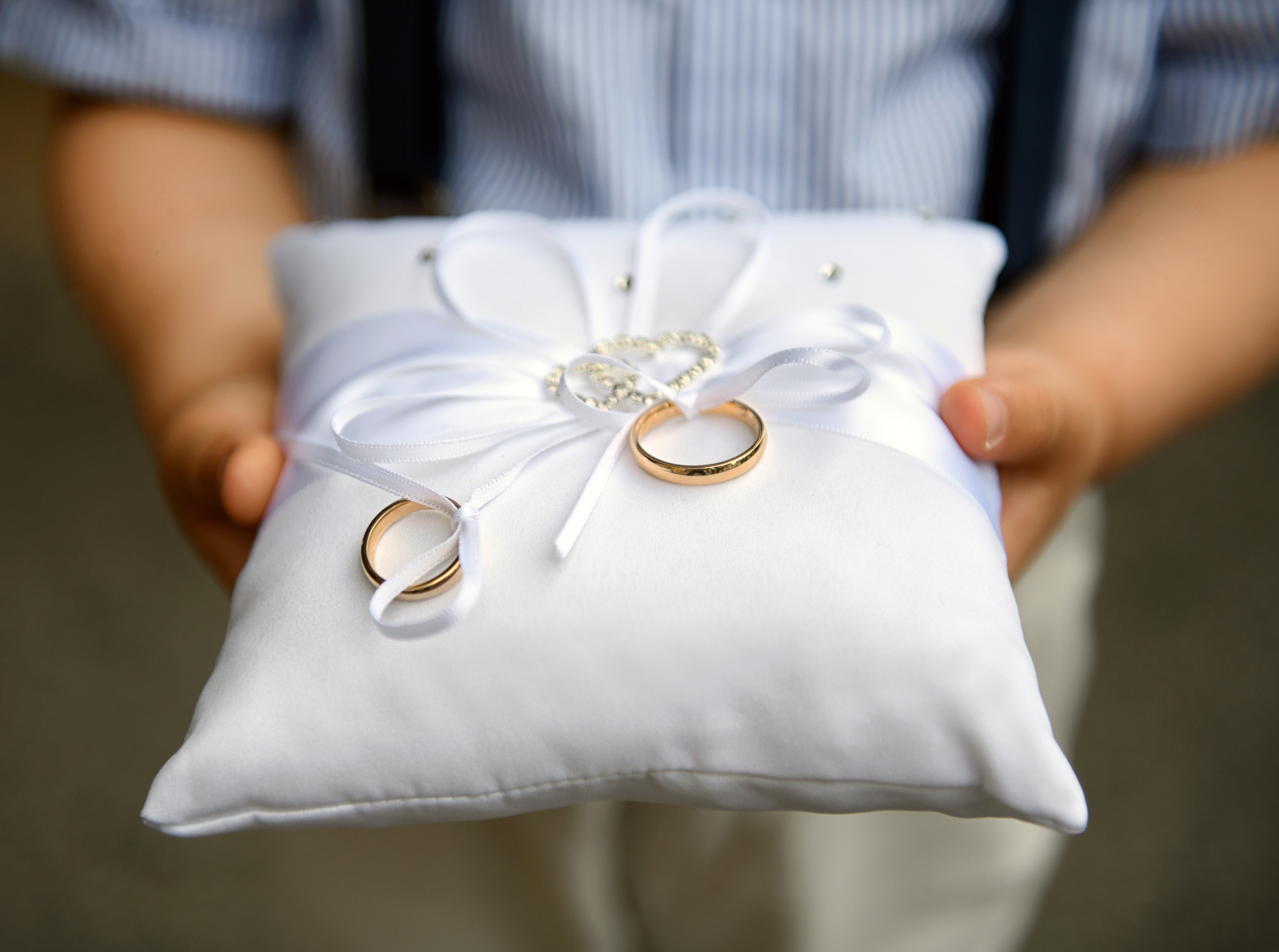 Ring bearer holding pillow with rings tied in a bow