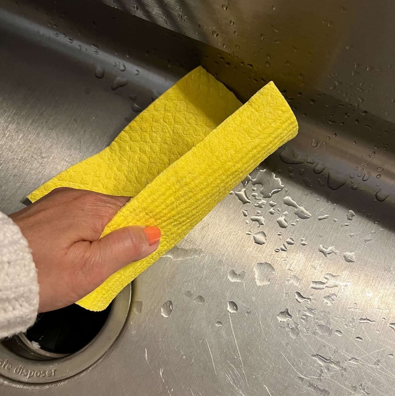 a reviewer photo of a hand using the yellow dishcloth to dry a sink