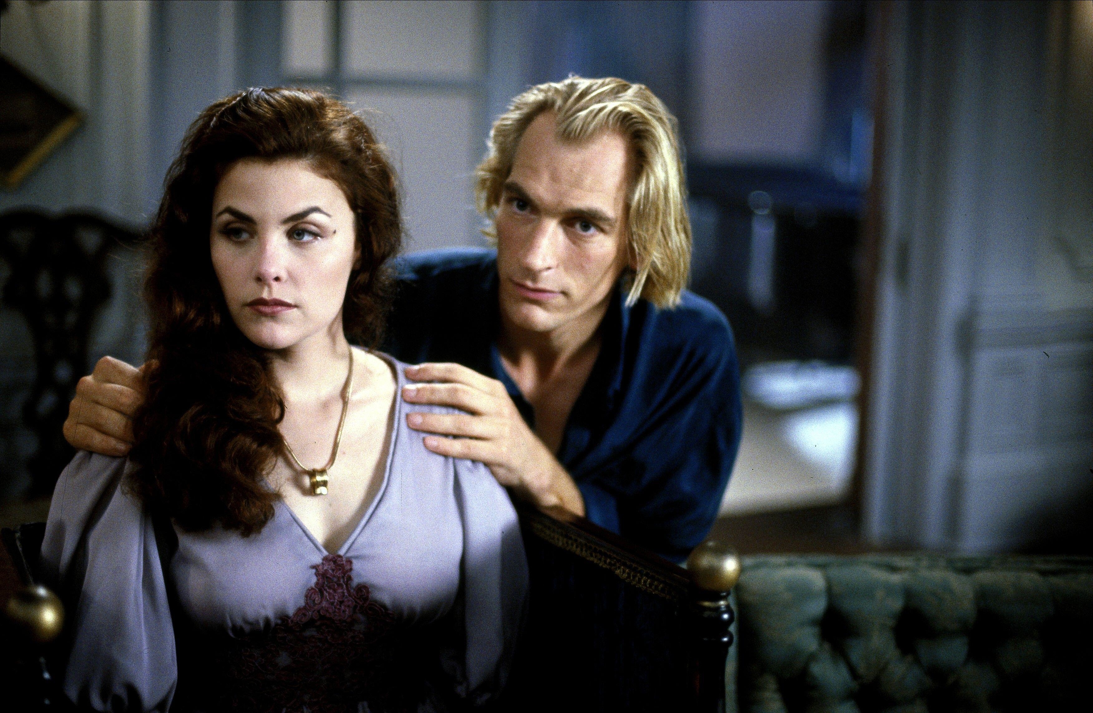 Julian Sands and Sherilyn Fenn sit together in a living room