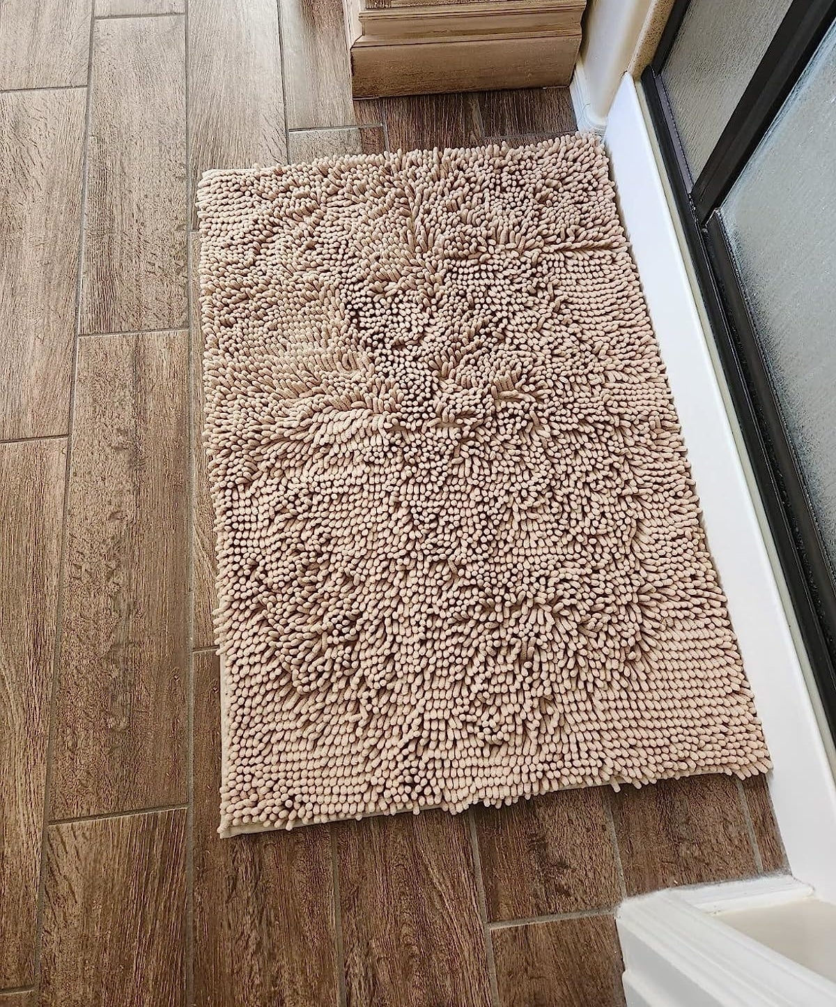 a reviewer photo of the tan bath mat on a bathroom floor