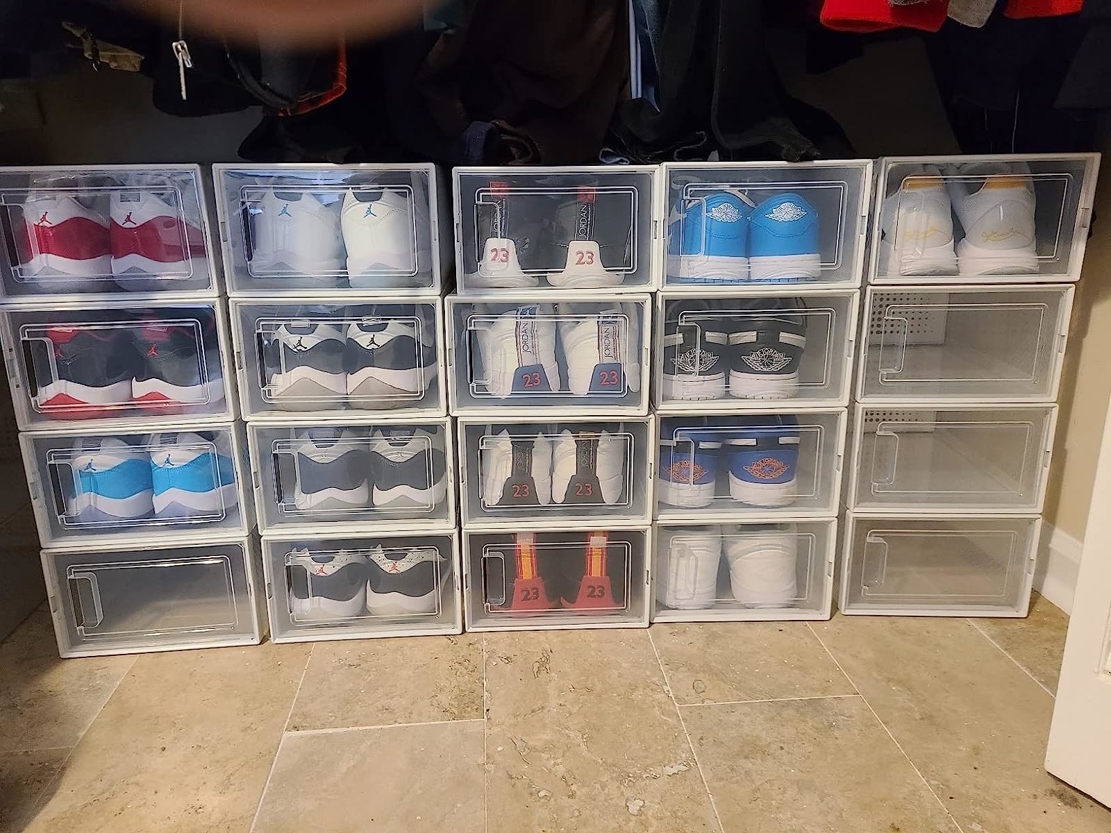 a reviewer photo of the clear boxes with colorful sneakers on the floor of a closet
