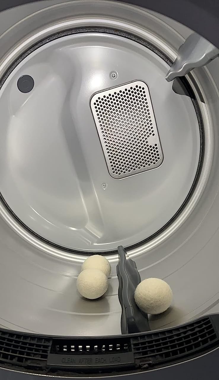 a reviewer photo of the white wool balls inside of a dryer