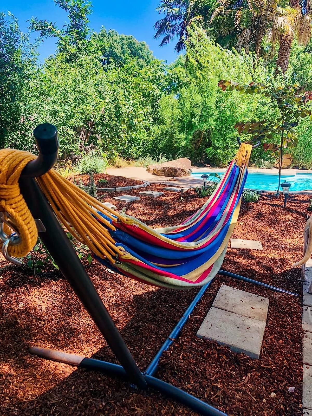 a reviewer photo of the brightly colored hammock in a decorated backyard