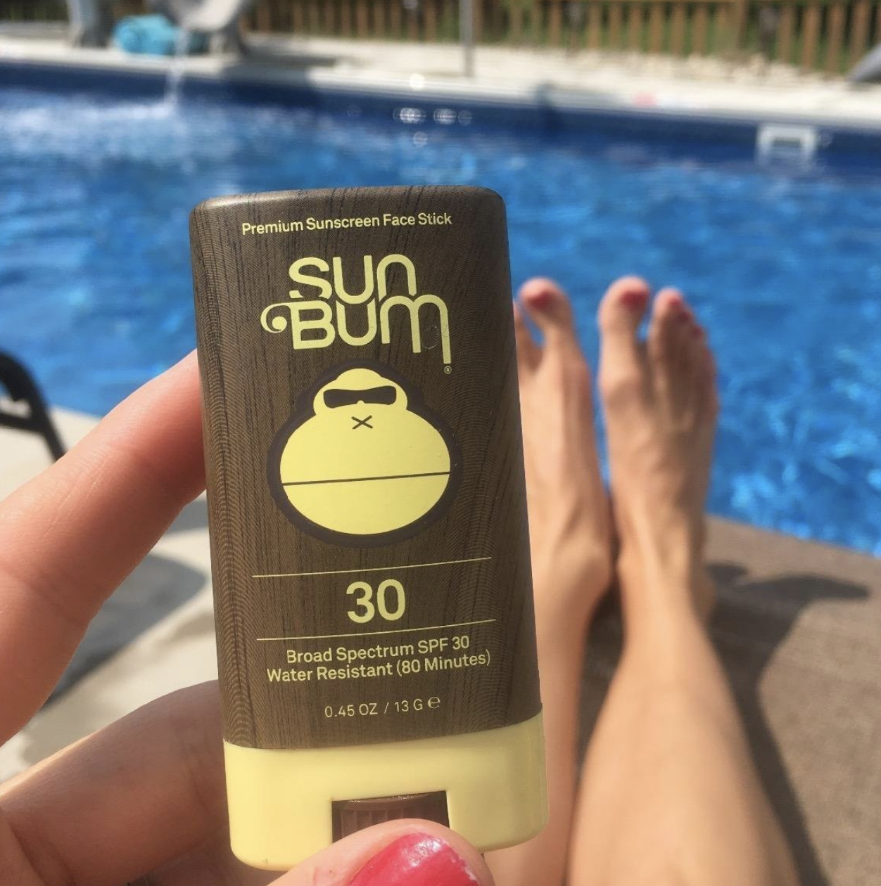 a reviewer with the sunscreen stick by the pool
