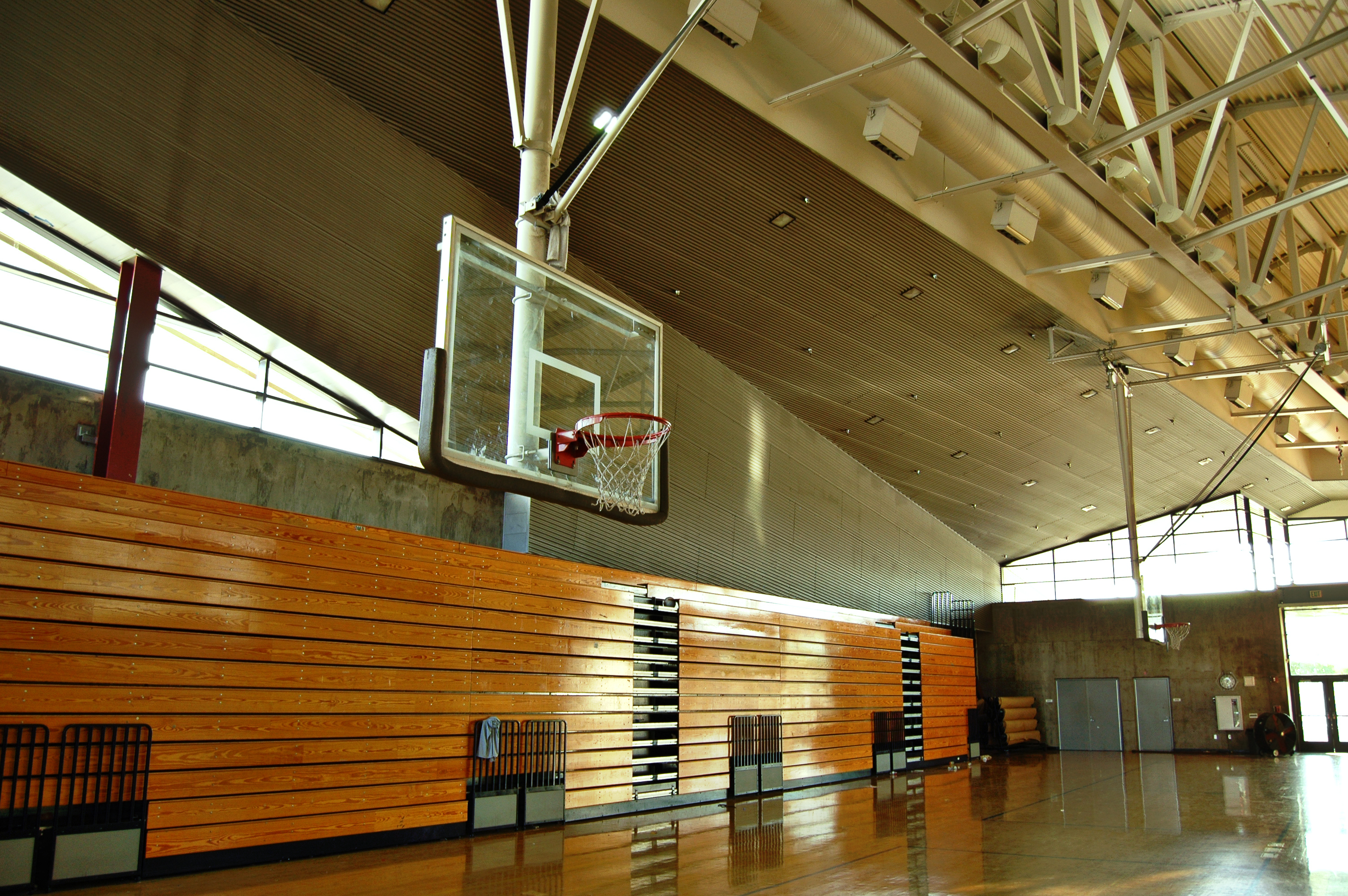 A high school gym with stacked bleachers and a basketball hoop