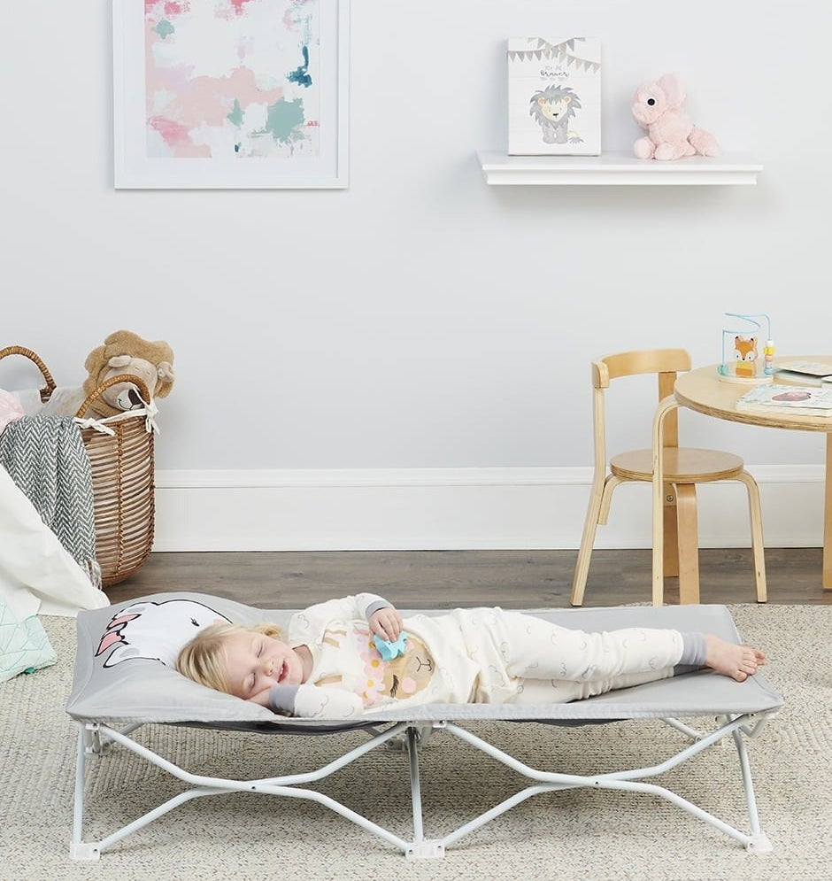 A child sleeping on the cot in a kid&#x27;s bedroom.