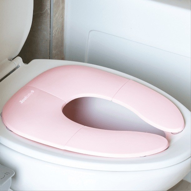 A pink travel potty seat over top of a normal size toilet seat.