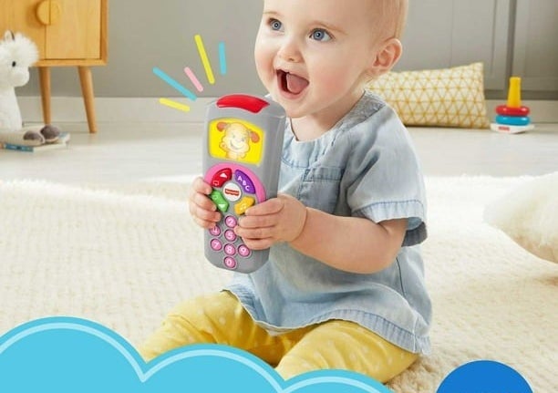 A child holding the toy remote while sitting on the floor.